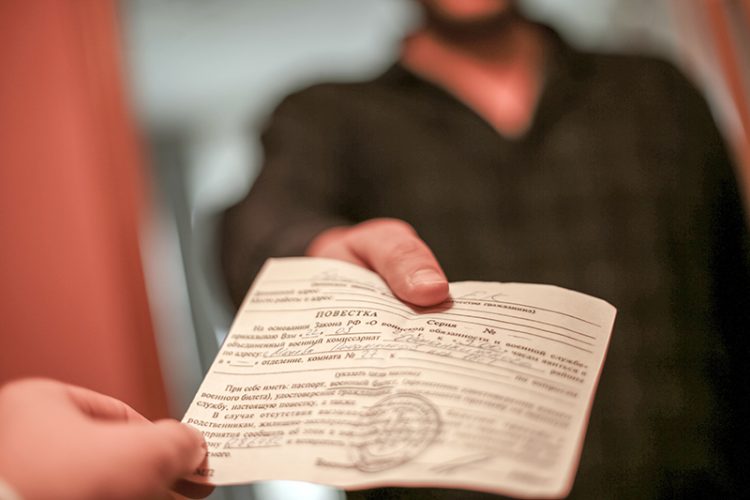 A summons from the military enlistment office in the hands of a young man.
