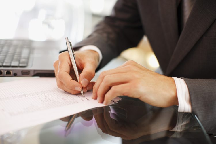 Businessman writing on paper at desk