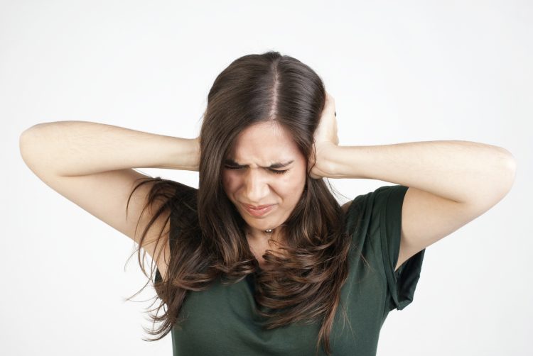 Young woman with his hands covering his ears not to hear noise.