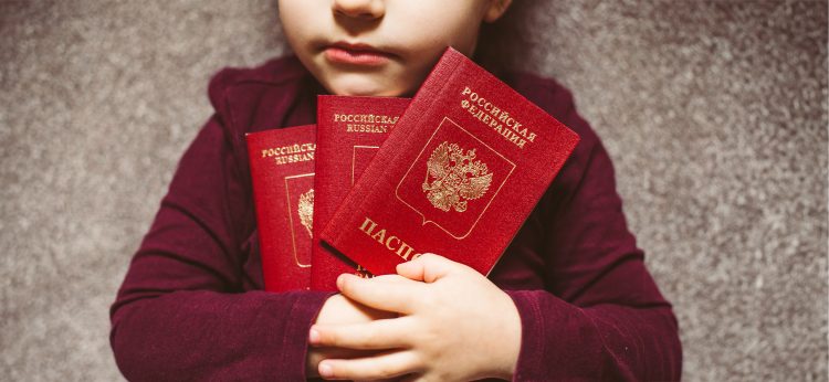 a girl holds in her hands three red passports with the inscription Russian Federation in Russian and English,