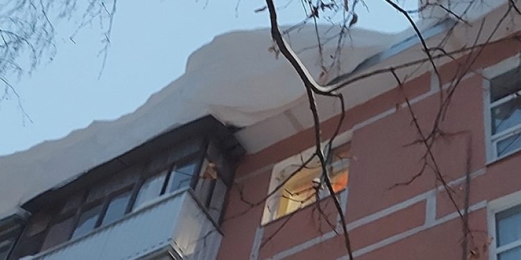 На улице Интернациональной с крыши дома свисает пласт снега