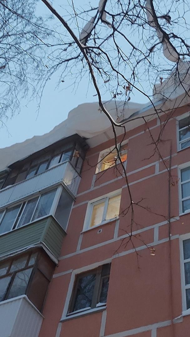 На улице Интернациональной с крыши дома свисает пласт снега